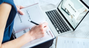 Close-up of a young woman searching for internships on her laptop and writing an application for an internship.