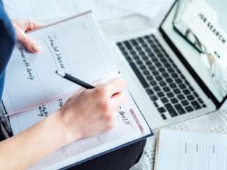 Close-up of a young woman searching for internships on her laptop and writing an application for an internship.