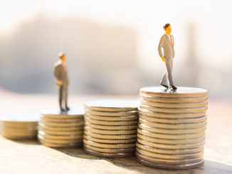 Miniature figures standing on stacks of coins of different heights