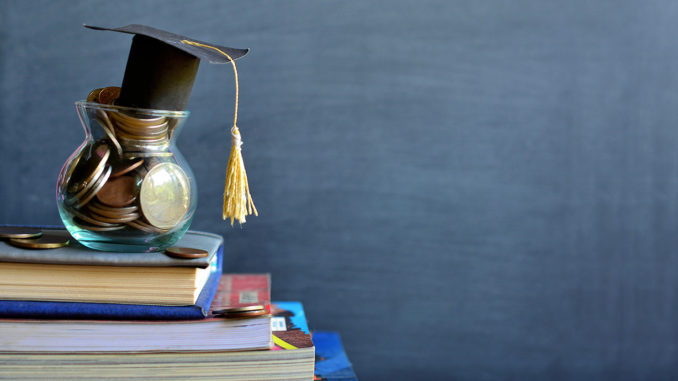 Concept of student financing: Graduation hat model on coins in a glass container on a stack of books