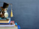 Concept of student financing: Graduation hat model on coins in a glass container on a stack of books