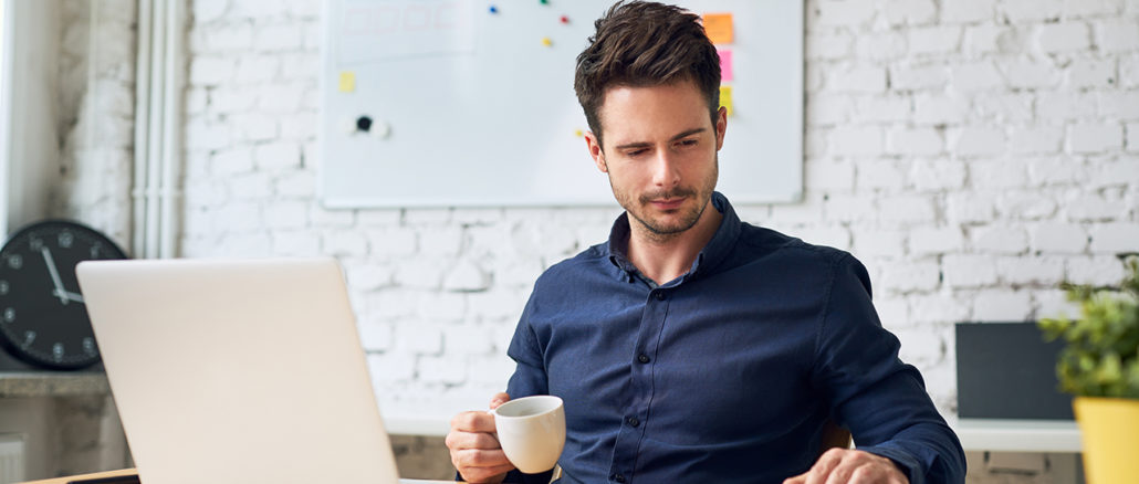 Focused working student holding cup of coffee and looking at important papers