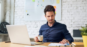Focused working student holding cup of coffee and looking at important papers
