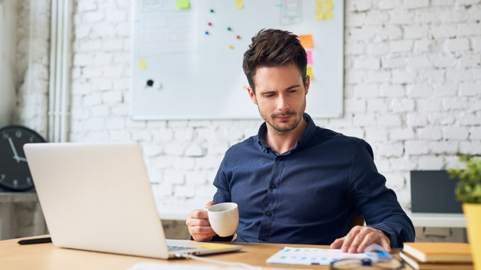 Focused working student holding cup of coffee and looking at important papers