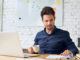 Focused working student holding cup of coffee and looking at important papers