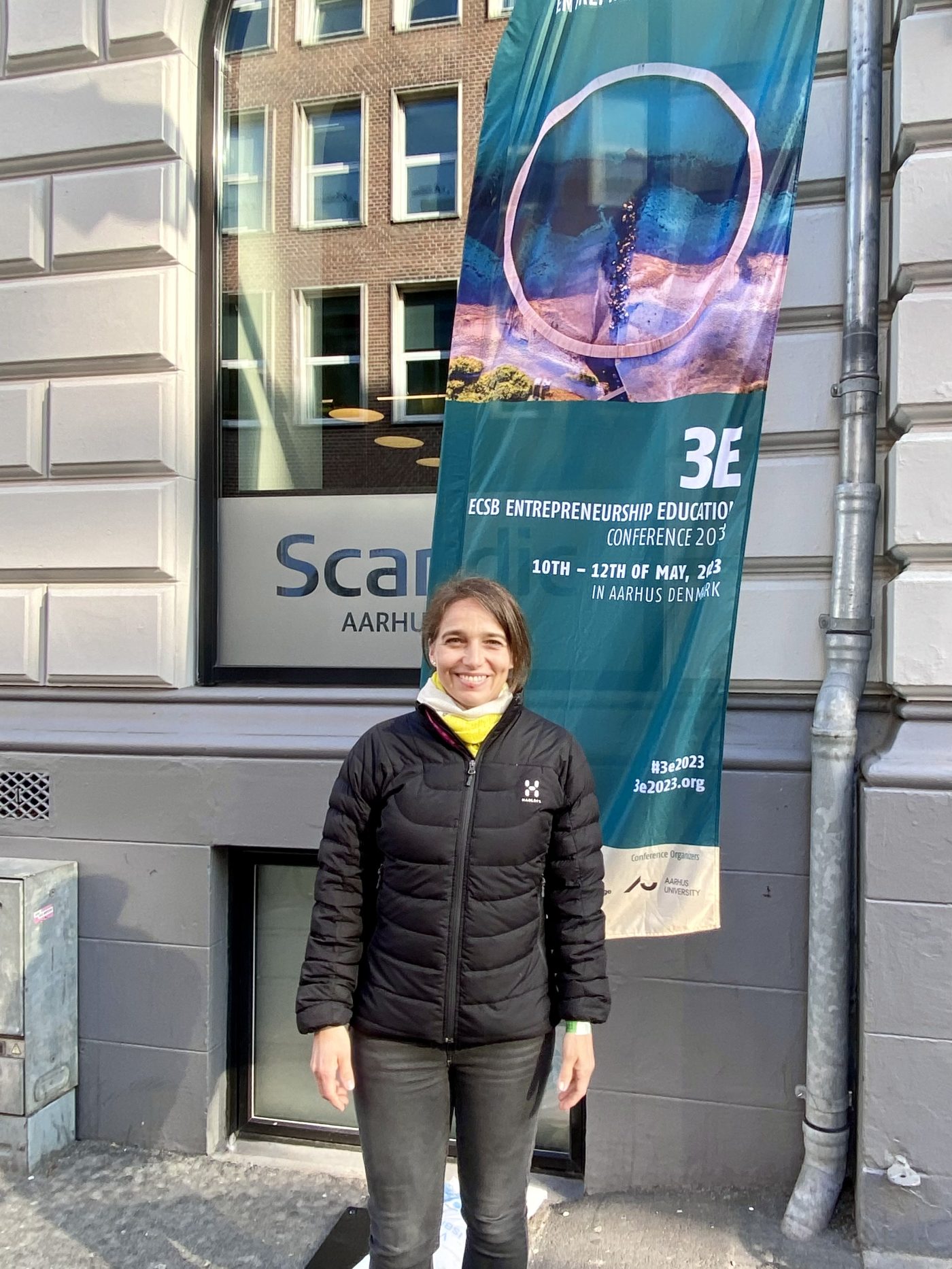 Dr. Barbara Wolf, lecturer at Munich Business School, in front of the 3E 2023 Conference display in Aarhus, Denmark.