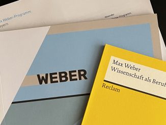 Top view of documents on the Max Weber Program, onto which Lucas Reischl, student of Munich Business School was accepted: Certificate of Admission, Reclam booklet by Max Weber "Wissenschaft als Beruf".