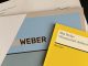 Top view of documents on the Max Weber Program, onto which Lucas Reischl, student of Munich Business School was accepted: Certificate of Admission, Reclam booklet by Max Weber "Wissenschaft als Beruf".