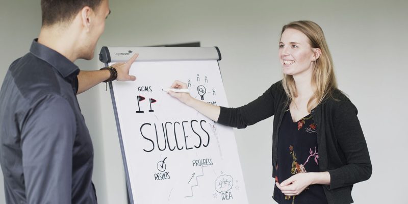 Two students from Munich Business School standing together at a flipchart with 
